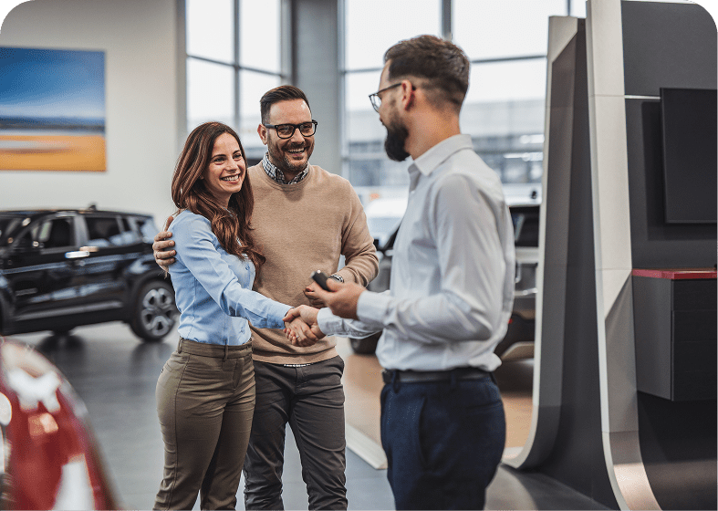 Couple shaking hands with car dealer